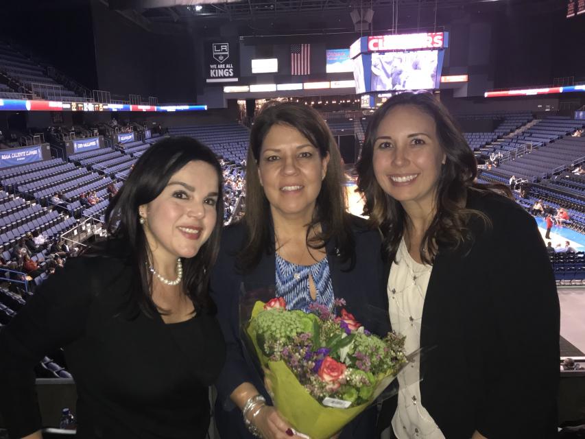 Three women standing in a stadium with  a bouquet of flowers